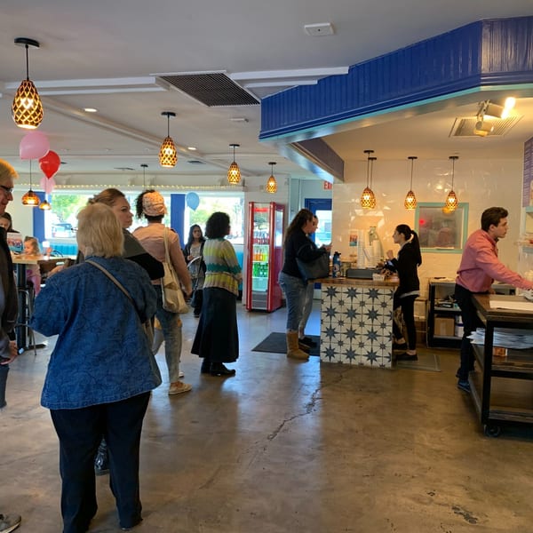 Customers line up at the counter of Niro's Gyros, a Greek restaurant with blue and white decor.
