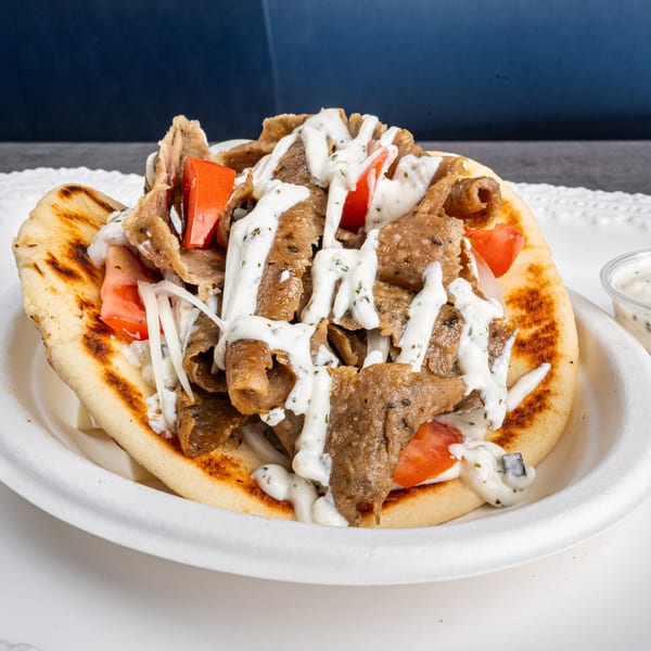 Niro's Gyros pita bread filled with meat, tomatoes, onions, and drizzled with tzatziki sauce.