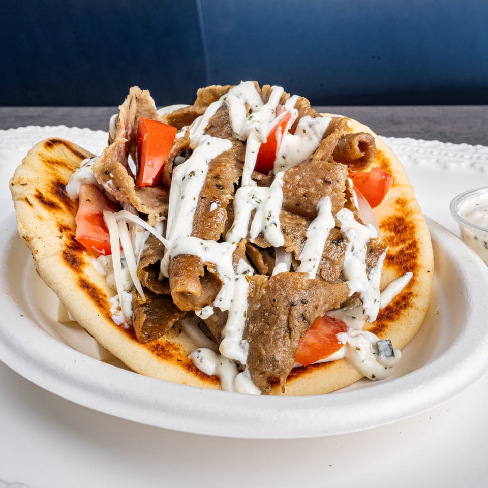 Niro's Gyros pita bread filled with meat, tomatoes, onions, and drizzled with tzatziki sauce.