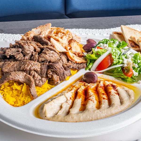 Niro's Gyros platter with beef and chicken gyros, yellow rice, hummus, Greek salad, and pita bread.