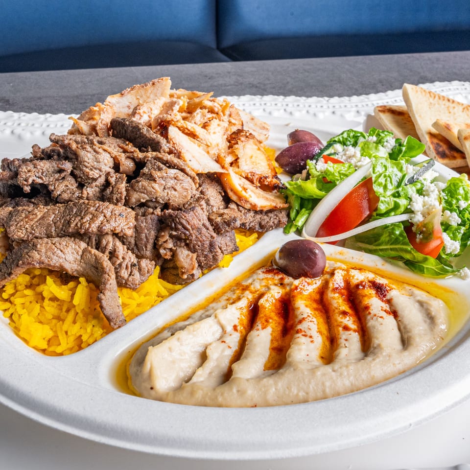 Niro's Gyros platter with beef and chicken gyros, yellow rice, hummus, Greek salad, and pita bread.