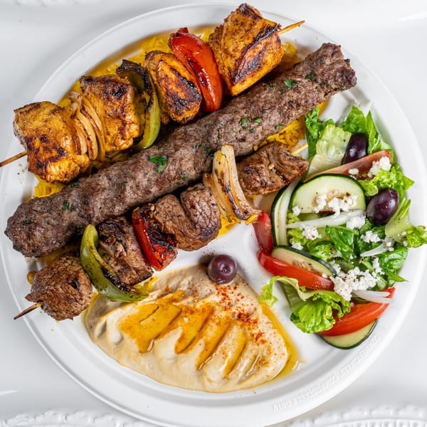 Niro's Gyros platter with chicken and beef skewers, gyro meat, hummus, rice, and Greek salad.